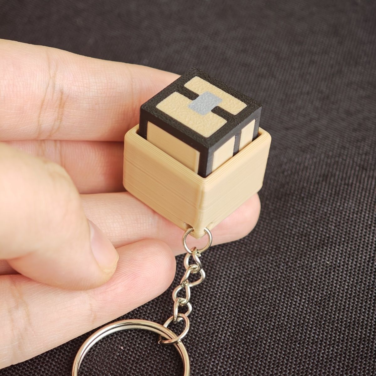 Wooden keychain with a small electronic component held in a hand against a dark background