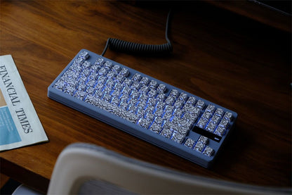 Mechanical keyboard with a coiled cable on a wooden desk with White Ink Swirl Side Engraved Keycaps on it