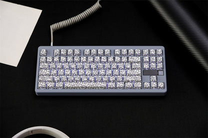 White Ink Swirl Side Engraved Keycaps of FancyKeebs in on a keyboard with coiled cable on a desk.